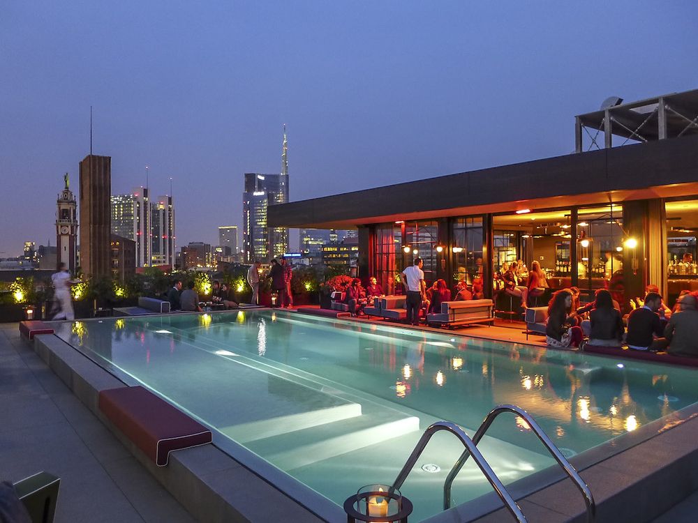 Milan rooftop pool at dusk with city skyline